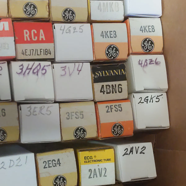 Collection of electronic tube boxes with various brands and model numbers on a cardboard surface.